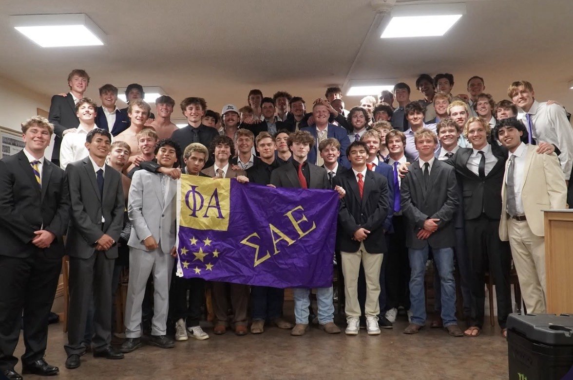 Wyoming Alpha brothers and new members holding the chapter flag at Fall 2026 initiation